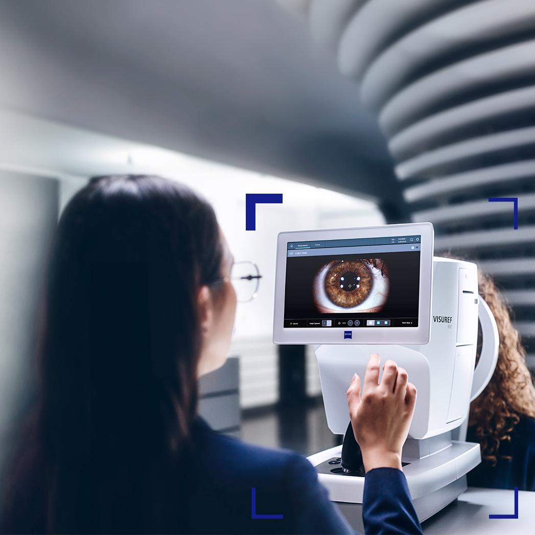 A female eye care professional looking at the ZEISS VISUREF 600 screen showing an image of an eye.