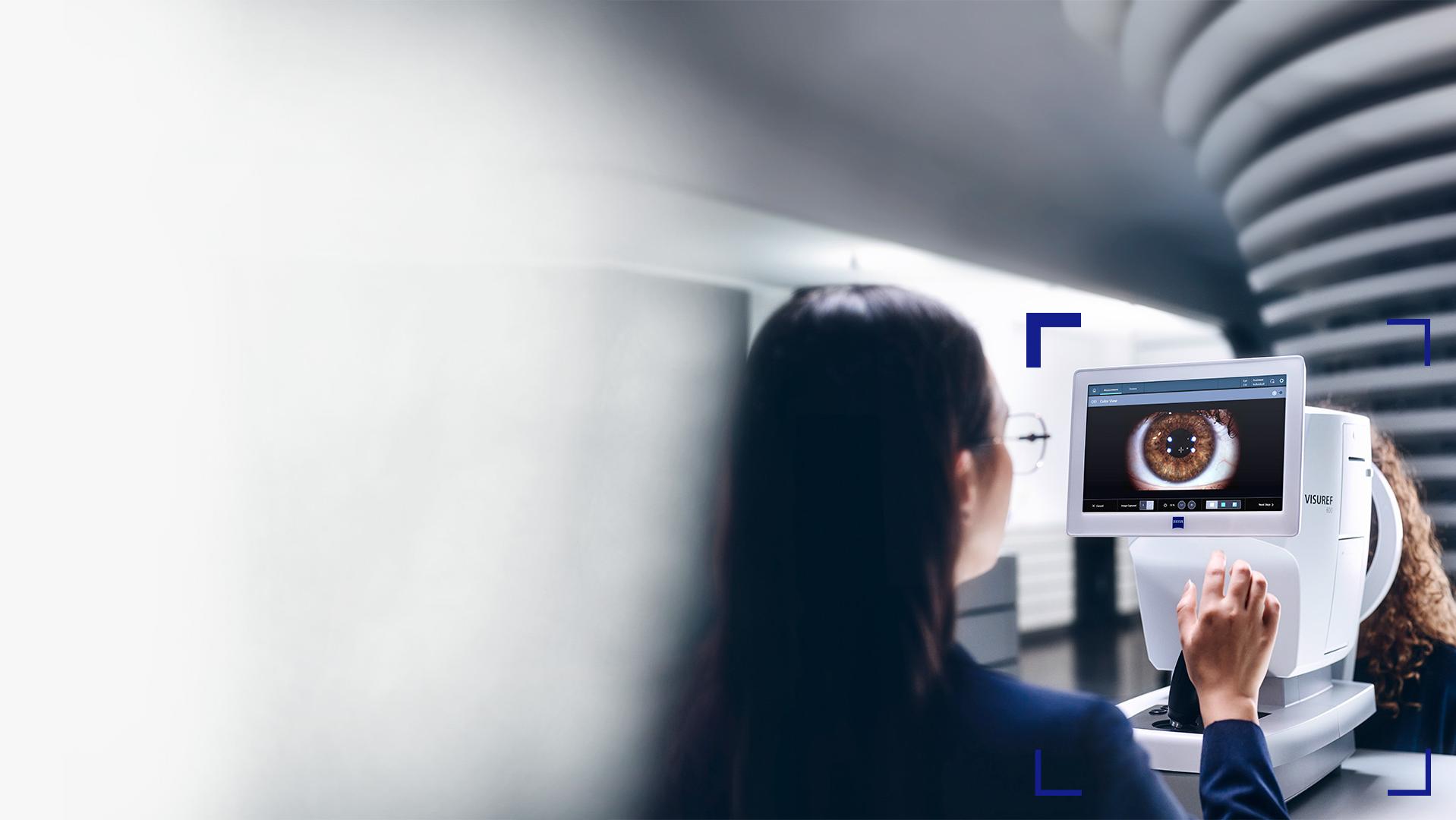 A female eye care professional looking at the ZEISS VISUREF 600 screen showing an image of an eye.