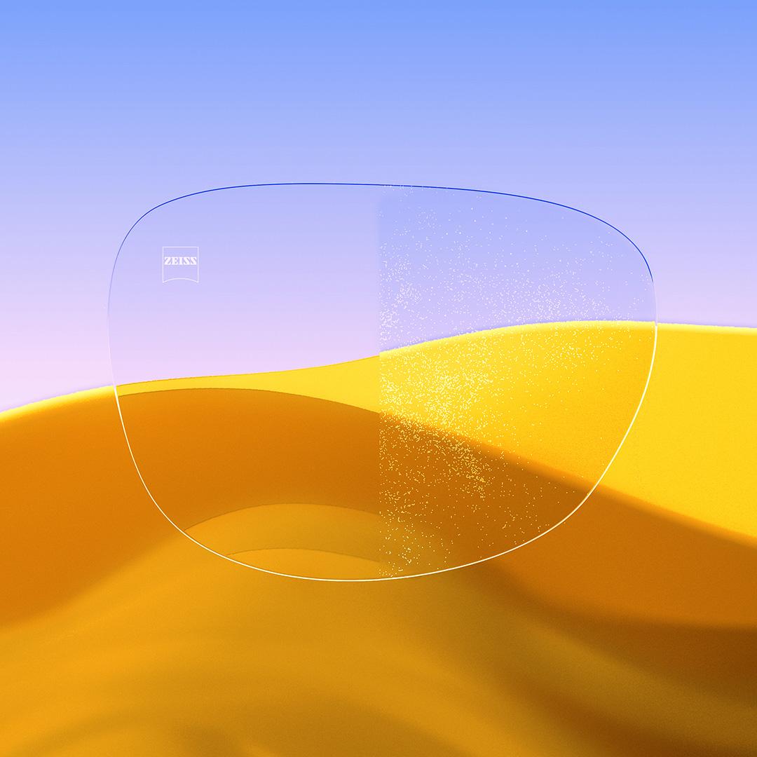 A split eyeglass lens with one side being clear and clean, featuring ZEISS DuraVision Gold UV and one side with dust covering the lens.