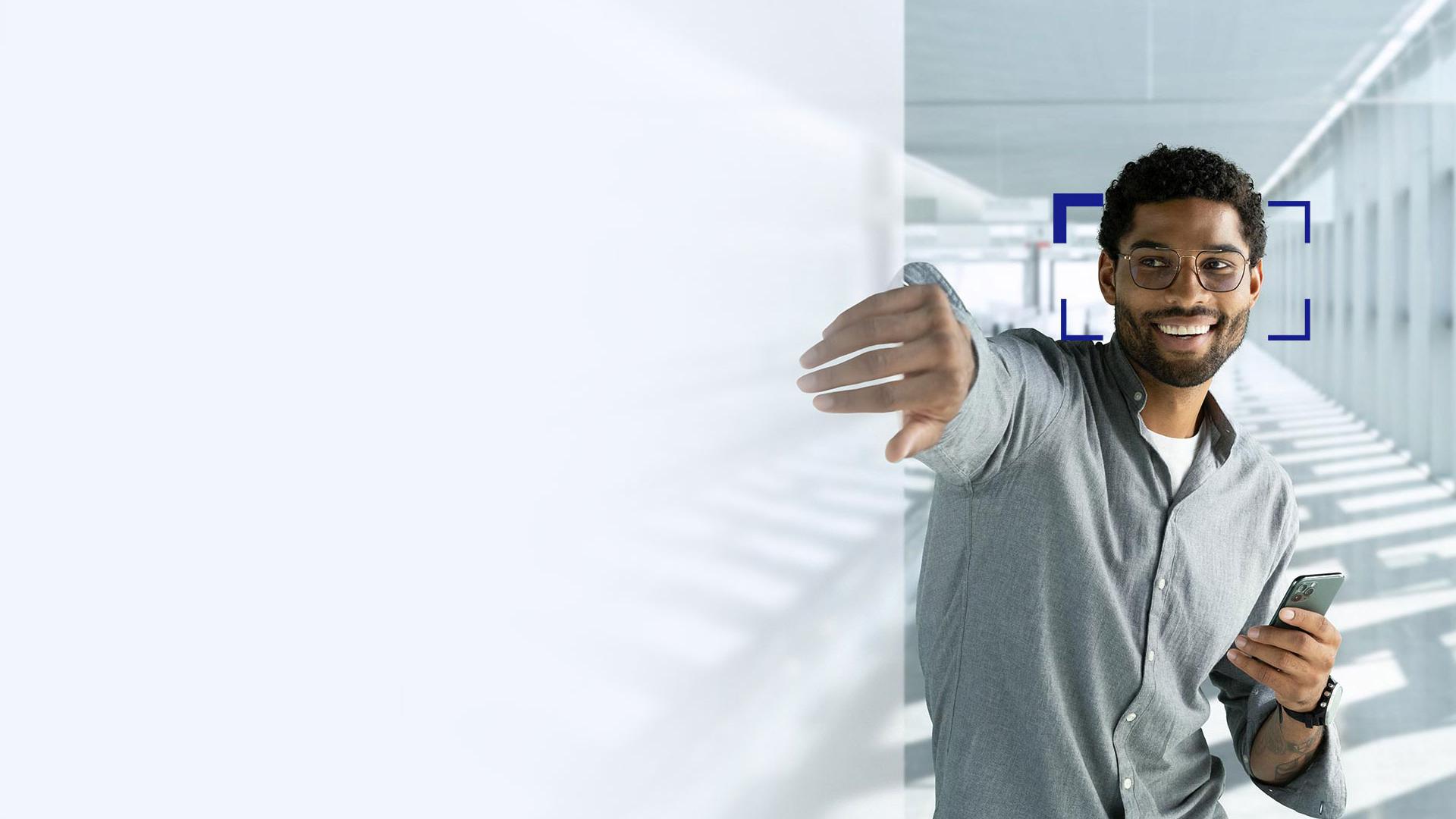 A young man with black hair wearing ZEISS SmartLife lenses; he is smiling and reaching with his hand through the screen.