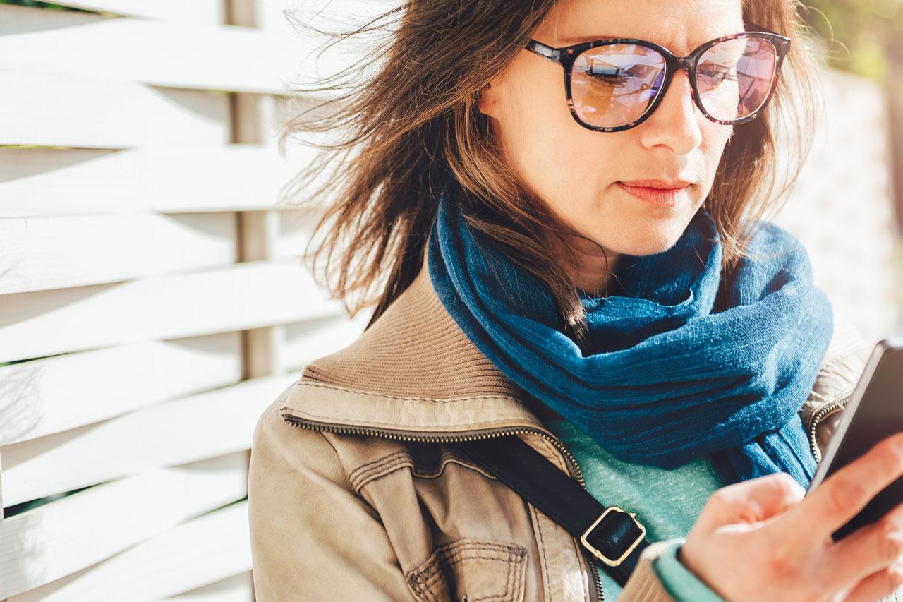 Femme tenant un café à emporter et utilisant un smartphone