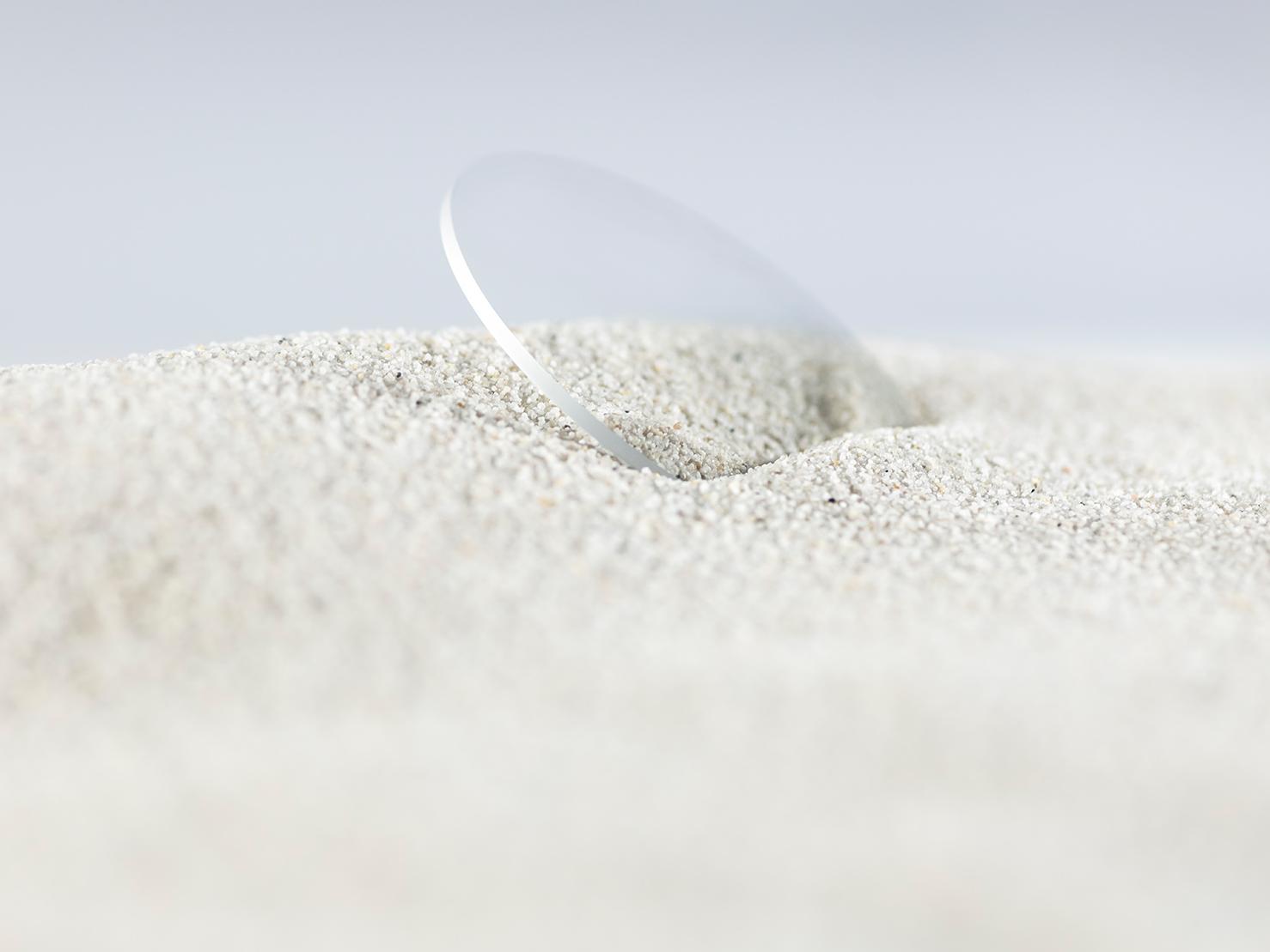Un verre ZEISS avec un traitement durable est couvert de sable sans présenter de rayures.