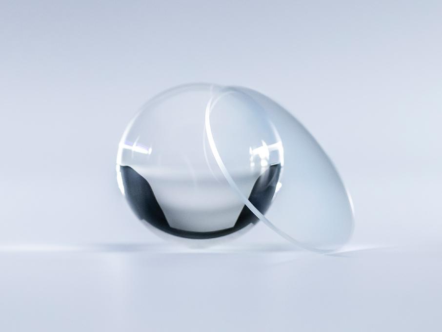 Un verre avec un traitement ZEISS Platinum est clair comme du cristal, sans aucun reflet, par rapport à la balle en verre se trouvant à côté.