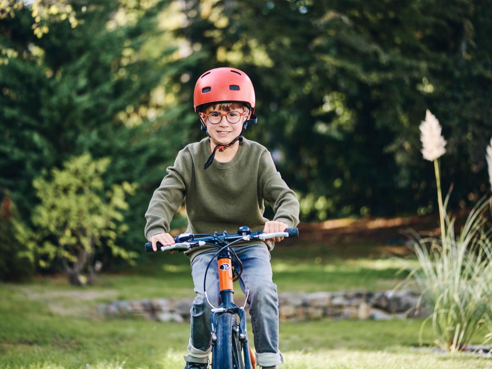 Un jeune garçon portant des verres ZEISS sur son vélo en extérieur.