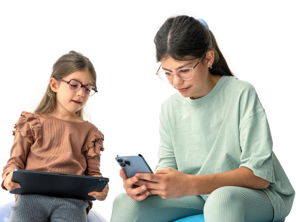 Deux fillettes regardent des appareils numériques à la distance suggérée de plus de 20 cm.