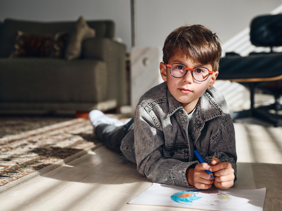 Un jeune garçon qui porte des verres ZEISS MyoCare regarde droit dans l’appareil photo.
