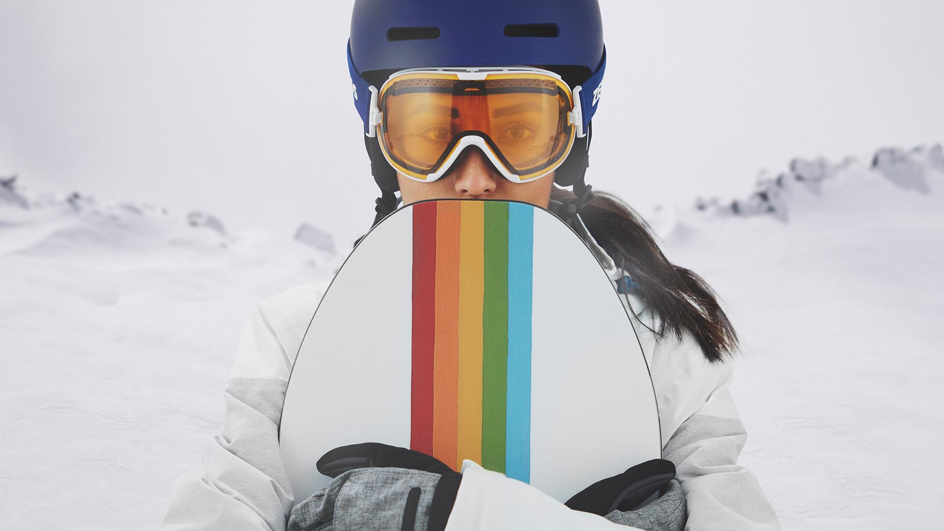 A woman wearing a blue helmet and ZEISS ski goggles with a transparent visor.