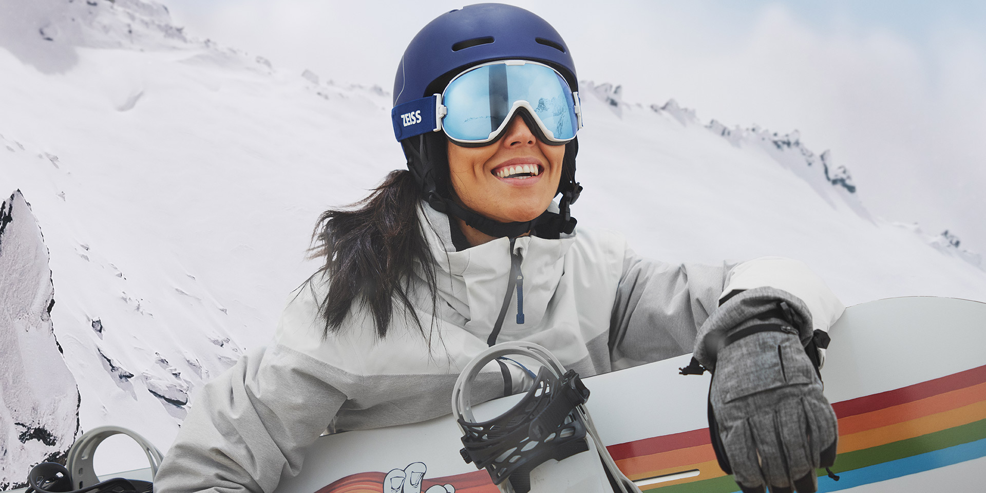 A young woman wearing snow goggles with ZEISS Interchangeable technology and holding a snowboard.