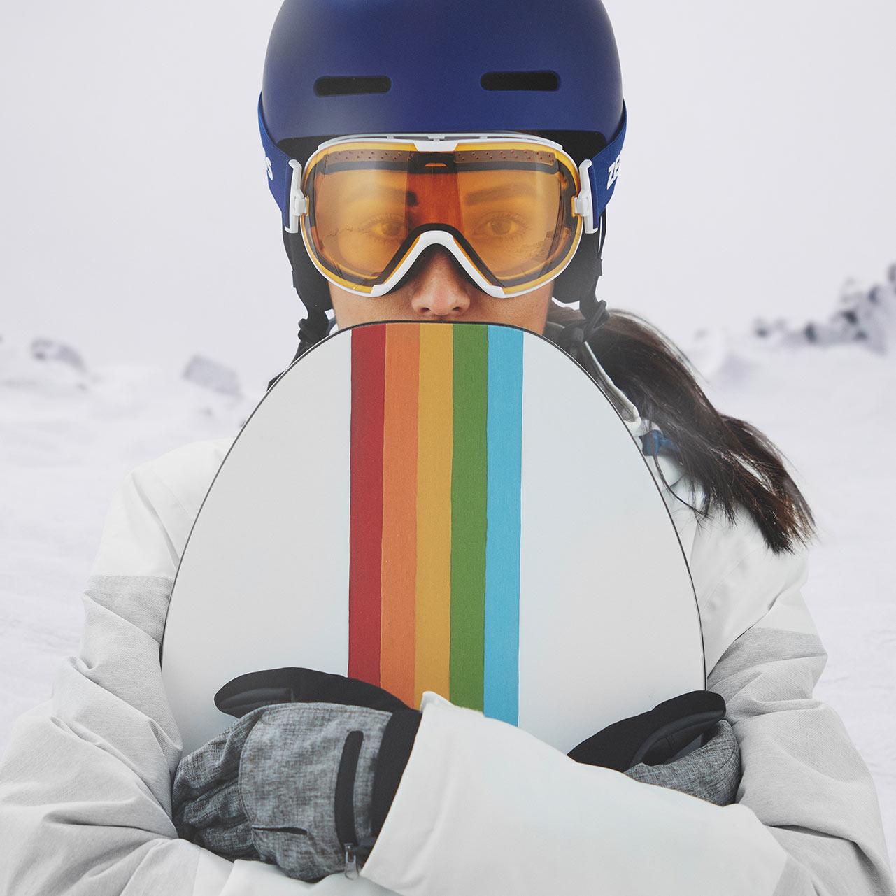 A woman wearing a blue helmet and ZEISS ski goggles with a transparent visor.