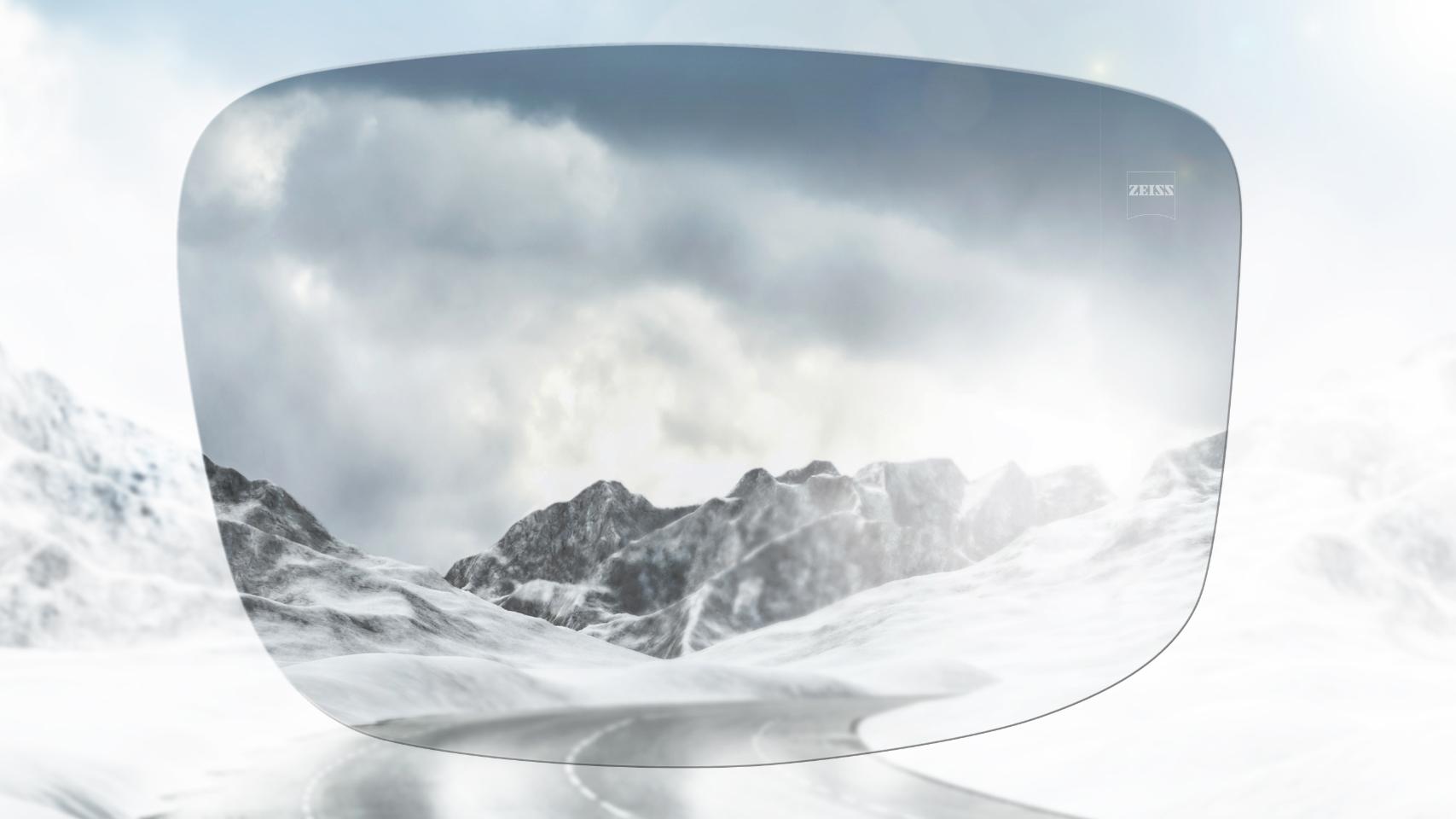 View of a snowy mountain road with and without polarized glasses. With polarized sunglasses, glare is reduced for a much clearer view ahead.