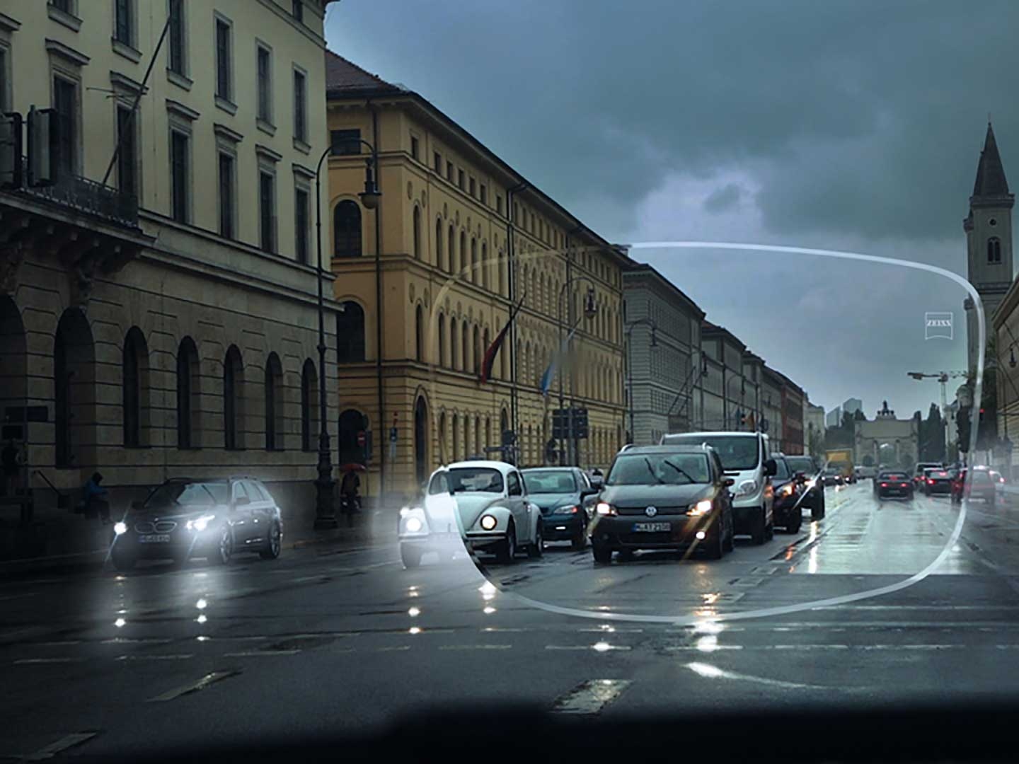 The image shows poor visibility in low-light conditions on a street. The point of view is the interior of a car as seen through a spectacle lens. 