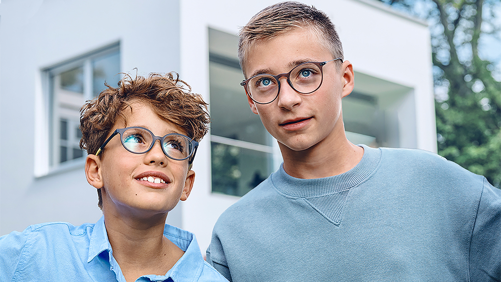 Un jeune garçon lève les yeux vers un adolescent, tous deux portent des lunettes ZEISS Single Vision SmartLife Young